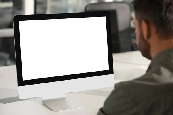 Man using modern computer at white desk in office, back view. Mockup for design