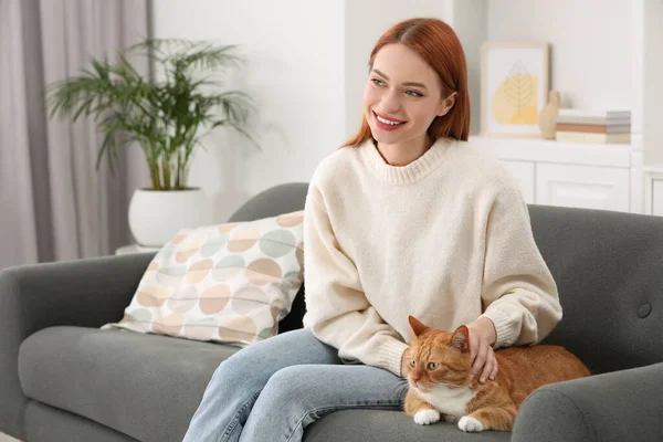 Woman with her cute cat on sofa at home