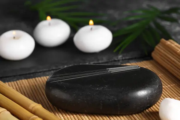 Stone with acupuncture needles on bamboo mat