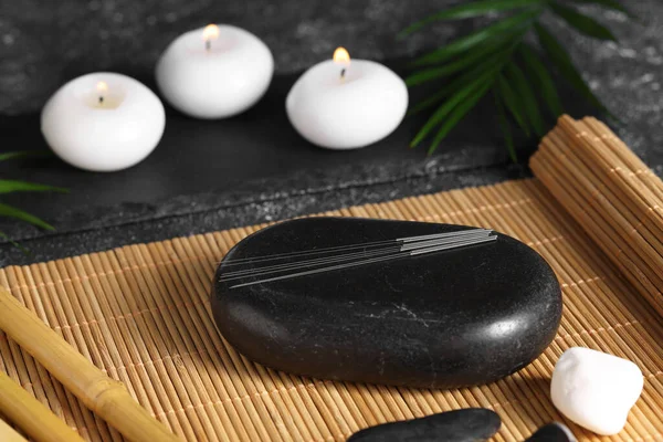 Stones with acupuncture needles on bamboo mat