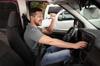 Favori radyoyu seçiyorum. Yakışıklı adam arabadaki araç ses düğmesine basıyor