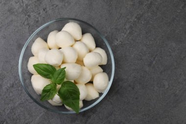 Lezzetli mozzarella topları ve fesleğen yaprakları gri masada, üst tarafta. Metin için boşluk
