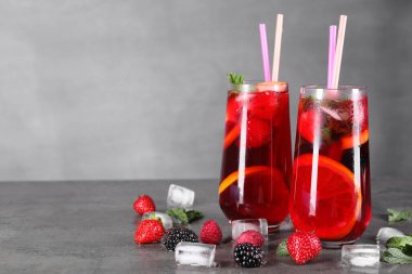 Lezzetli ferahlatıcı sangria, buz küpleri ve böğürtlenler gri masada, yazı için yer