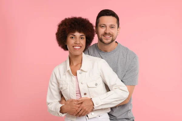 International dating. Happy couple hugging on pink background