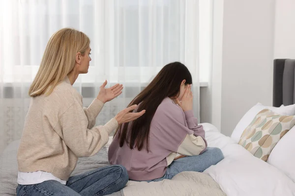 Mother consoling her upset daughter in bedroom. Teenager problems
