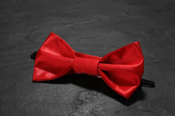 Stylish red bow tie on black table, closeup