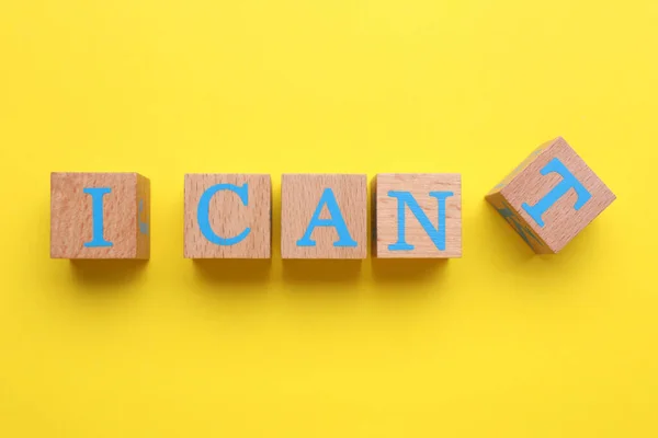 Stock image Motivation concept. Changing phrase from I Can't into I Can by removing cube with letter T on yellow background, top view