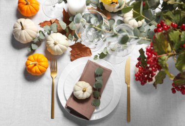 Güzel bir sonbahar sofrası. Tabaklar, çatal bıçak takımı, bardaklar, balkabakları ve çiçek dekoru.