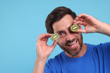 Açık mavi arkaplanda kivi parçaları tutan adam, metin için boşluk