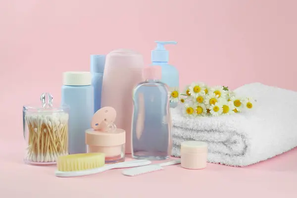 Different skin care products for baby, flowers and accessories on pink background