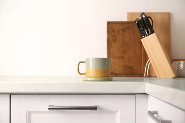 One ceramic mug with coaster on light countertop in kitchen