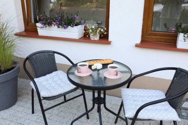 Bardaklar dolusu kahve, ekmek ve peynir cam masada. Açık terasta dinlenme yeri