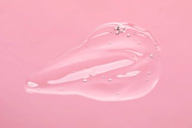 Açık pembe arka planda temizleme jeli örneği, üst manzara. Kozmetik ürünü