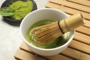 Açık gri masada bambu çırpıcılı taze kibrit çayı, yakın plan.