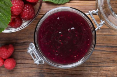 Lezzetli ahududu reçeli kavanozu ve ahşap masada taze böğürtlen.