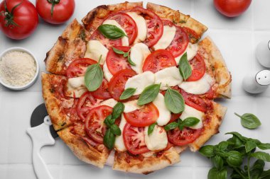 Lezzetli domatesli Caprese pizzası, mozzarella ve fesleğen beyaz fayanslı masada, düz yatıyordu.