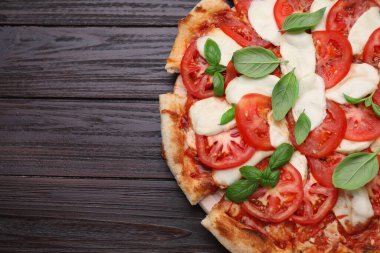 Domatesli lezzetli Caprese pizzası, mozzarella ve fesleğen, koyu ahşap masa, üst manzara. Metin için boşluk