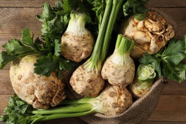 Fresh raw celery roots and sack on wooden table, top view clipart