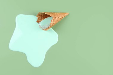 Yeşil arka planda erimiş dondurma ve gofret külahı. Metin için boşluk