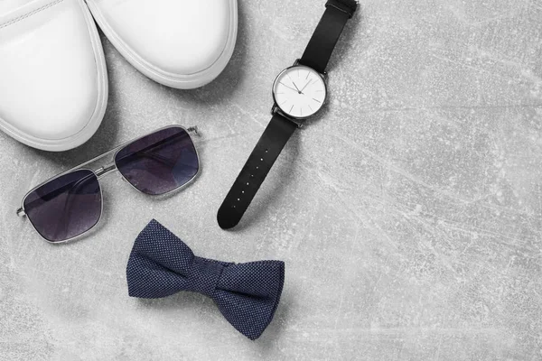 Stylish blue bow tie, shoes, sunglasses and wristwatch on light grey table, flat lay. Space for text