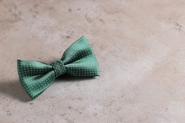 Stylish green bow tie on gray textured background, space for text