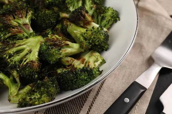 Tasty fried broccoli in bowl on table, closeup