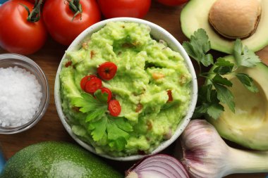 Lezzetli guacamole ve malzemeler ahşap masada, düz yerde.