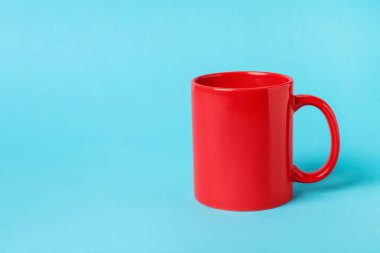 Açık mavi arkaplanda bir kırmızı seramik bardak, metin için boşluk