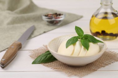 Lezzetli mozzarella dilimleri, fesleğen yaprakları ve beyaz ahşap masada bıçak. Metin için boşluk