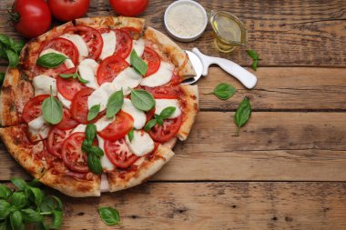 Domatesli lezzetli Caprese pizzası, mozzarella ve fesleğen ahşap masada servis edilir. Metin için boşluk