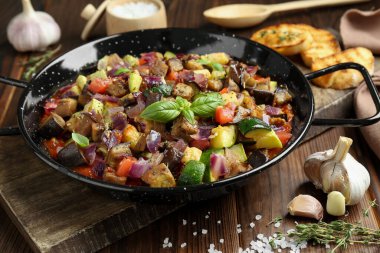 Pişirme kabında lezzetli ratatouille ahşap masada servis edilir, yakın plan.