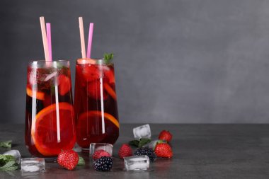 Lezzetli ferahlatıcı sangria, buz küpleri ve böğürtlenler gri masada, yazı için yer