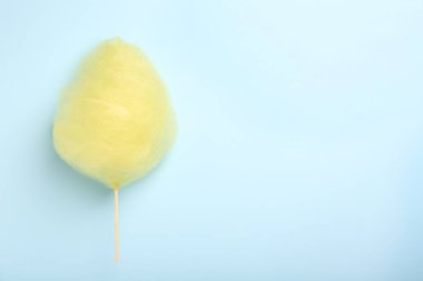 Açık mavi arka planda bir tane sarı pamuk helva, üst manzara. Metin için boşluk