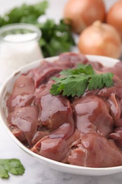 Beyaz masada maydanozlu çiğ tavuk ciğeri, yakın plan.