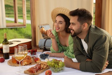 Romantik bir randevu. Güzel bir çift, ahşap çardakta piknik yapıyor.