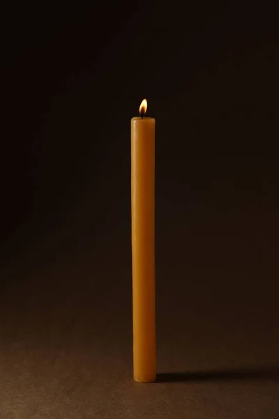 Burning church wax candle on dark background