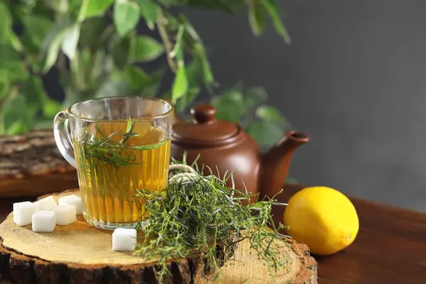 Aromatic herbal tea, fresh tarragon sprigs and sugar cubes on wooden table. Space for text