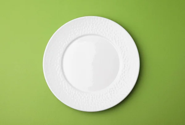 One clean plate on green background, top view