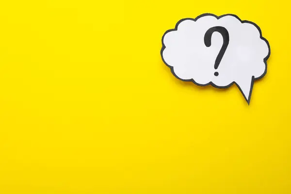 Paper speech bubble with question mark on yellow background, top view. Space for text