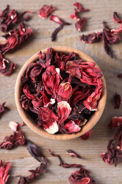 Dry hibiscus tea on wooden table, flat lay
