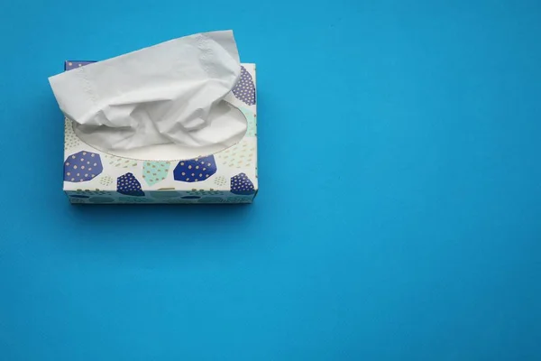 Box of paper tissues on light blue background, above view. Space for text