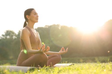 Güzel genç bir kadın yoga minderinde Padmasana egzersizi yapıyor. Düşük açılı görüş ve mesaj için yer. Lotus pozu