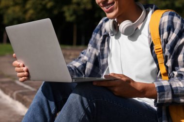 Öğrenci dışarıda dizüstü bilgisayarla çalışıyor, yakın plan.