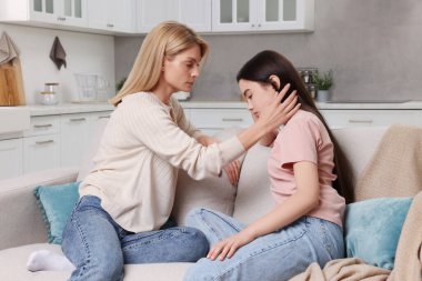 Anne, üzgün kızını evde teselli ediyor. Gençlik sorunları