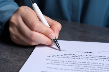 Gri masada kalemle belge imzalayan kadın, yakın plan