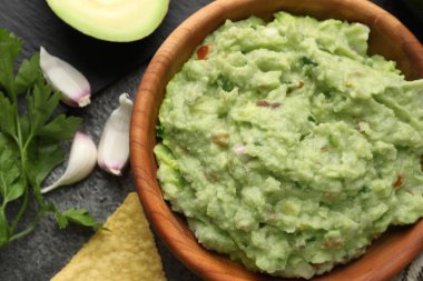 Lezzetli guacamole ve malzemeler gri masada, düz yerde.