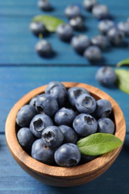 Mavi ahşap masada bir kase taze yaban mersini, yakın plan. Metin için boşluk