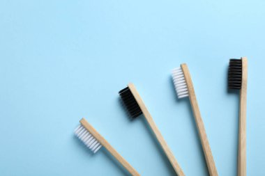 Açık mavi arka planda bambu diş fırçaları, düz. Metin için boşluk