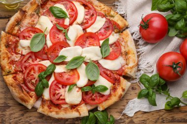 Domatesli lezzetli Caprese pizzası, ahşap masada mozzarella ve fesleğen.