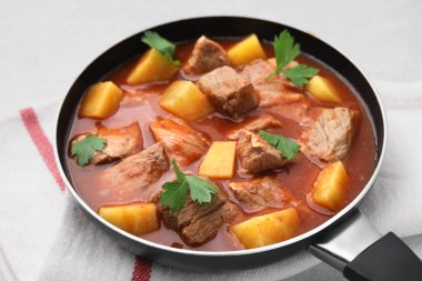 Açık gri masada tencerede leziz gulaş, yakın plan.